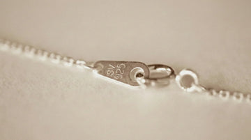 Close-up of a silver bracelet with '925' stamp on a beige background