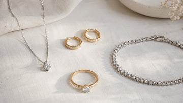 Minimalist moissanite jewelry capsule in 925 sterling silver and 14K gold filled — solitaire necklace, small hoops, bezel tennis bracelet, and solitaire ring for a quiet luxury look.
