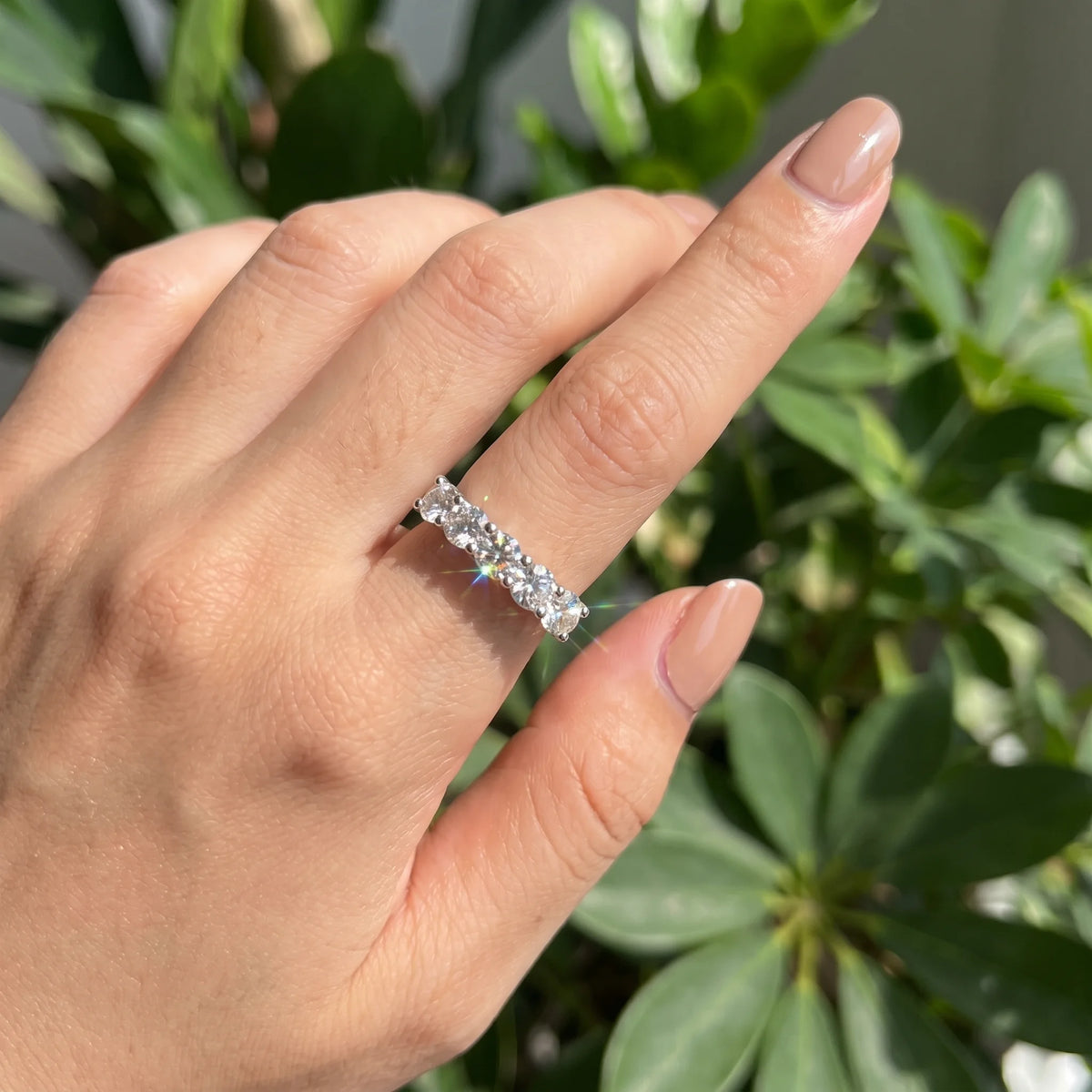 Hand wearing the 1.5ct five stone moissanite wedding band in white gold outdoors - Sensitive Stones