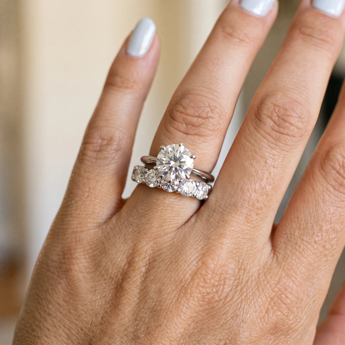 1.5ct five stone moissanite wedding band in white gold worn beside a solitaire engagement ring - Sensitive Stones