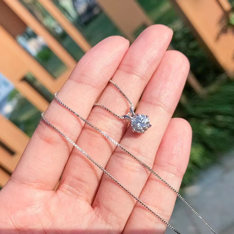 Hand holding a moissanite solitaire necklace for women, featuring a brilliant round-cut stone on a delicate sterling silver chain, perfect for quiet luxury pendants and everyday sparkle.