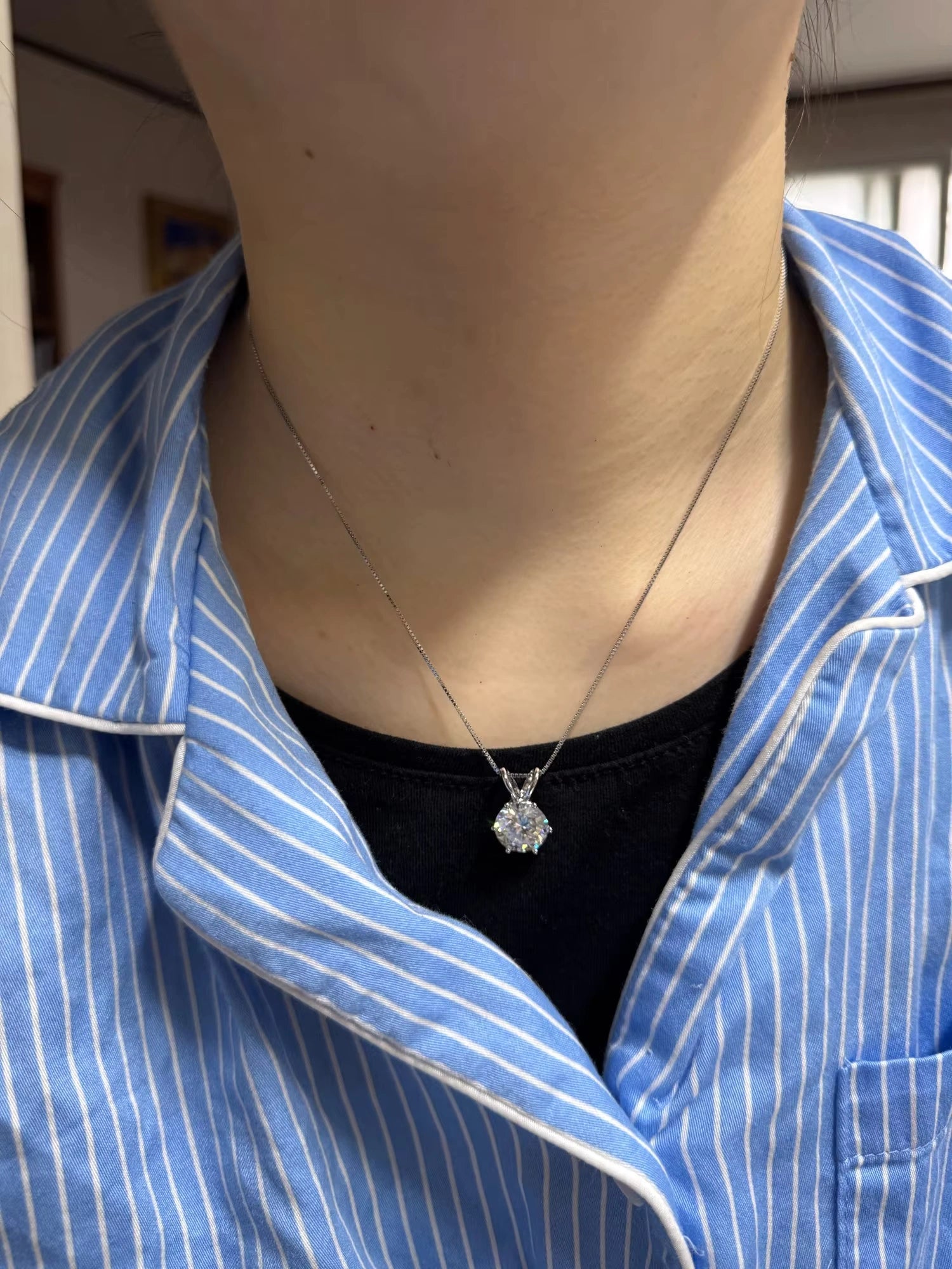 Classic moissanite solitaire pendant necklace styled with a blue striped blouse, a timeless choice for women’s moissanite jewelry lovers.