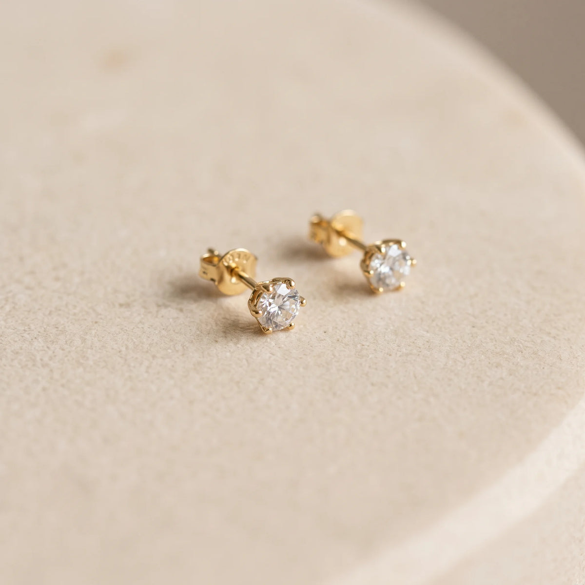 14K gold filled moissanite stud earrings in yellow gold resting on a ceramic dish with the butterfly push backs fitted - Sensitive Stones