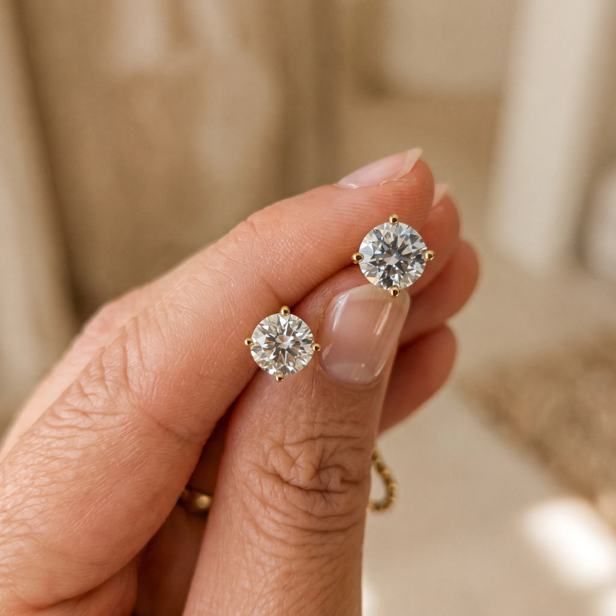14K gold filled moissanite solitaire stud earrings in yellow gold, pair held in hand to show size - Sensitive Stones