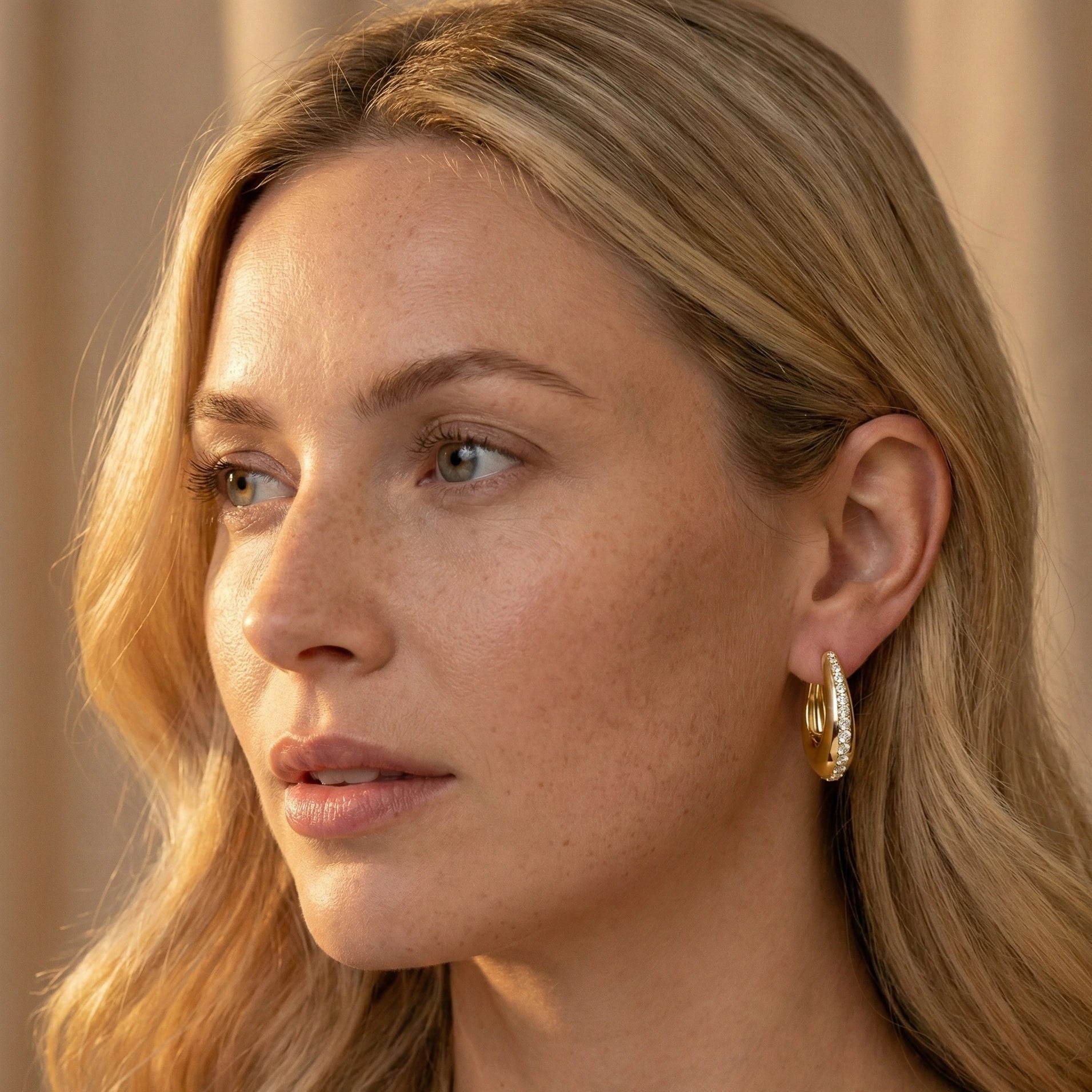 Close up of a woman wearing 14K gold filled moissanite chunky hoop earrings  bold pavé style, warm lighting - Sensitive Stones