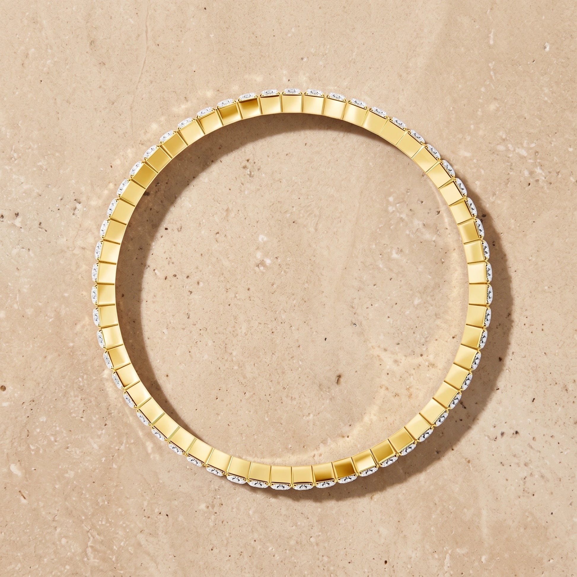 14K gold filled stretch moissanite tennis bracelet shown in a full circle on a beige stone surface