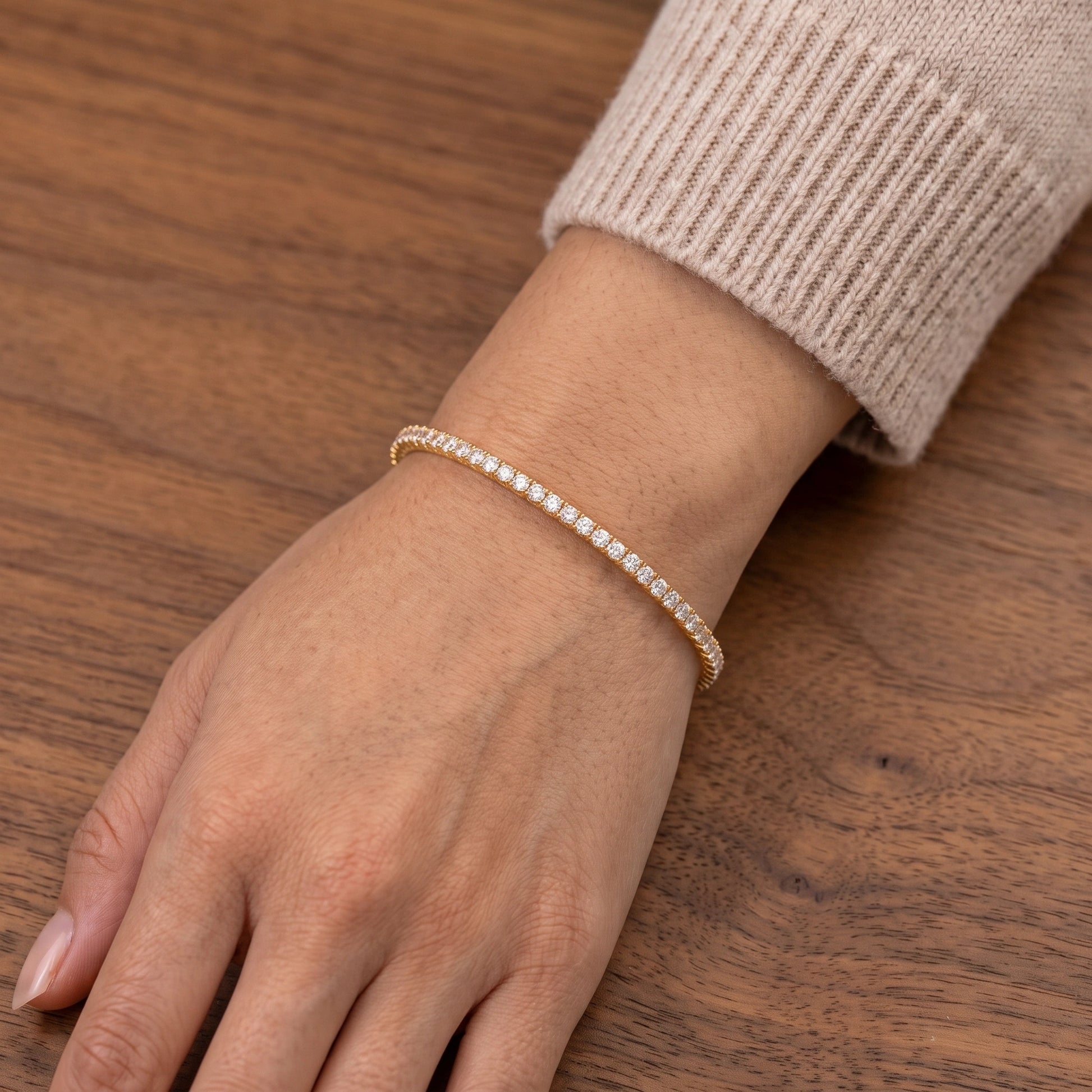 Dainty 14k gold filled moissanite stretch tennis bracelet worn on the wrist against a warm wood background