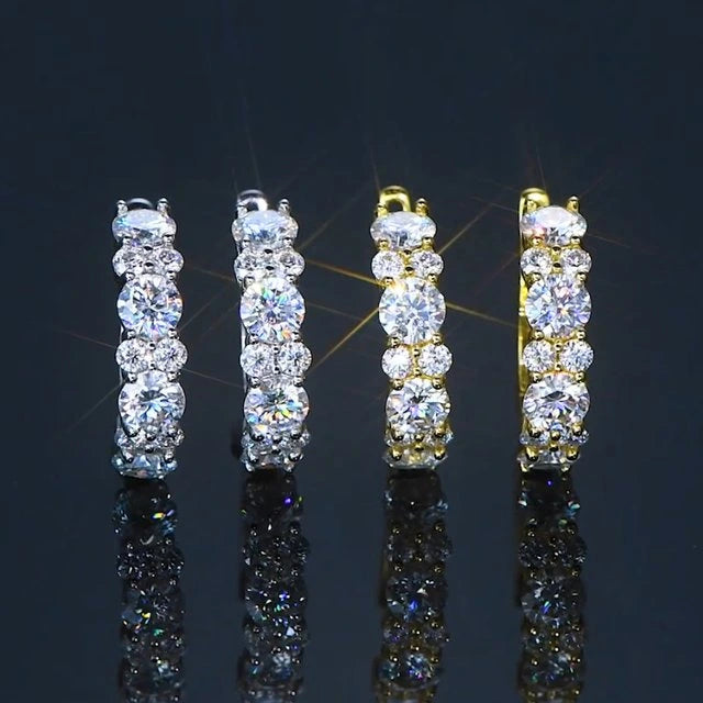 Pair of moissanite hoop earrings, one gold and one silver, set in 925 silver with white gold and yellow gold finish, on a reflective black surface - Sensitive Stones