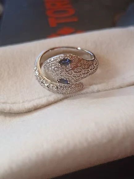 Close-up of moissanite snake ring with sapphire blue color stones for the eyes, crafted in sterling silver with detailed scales and high-polish 18K white gold finish.