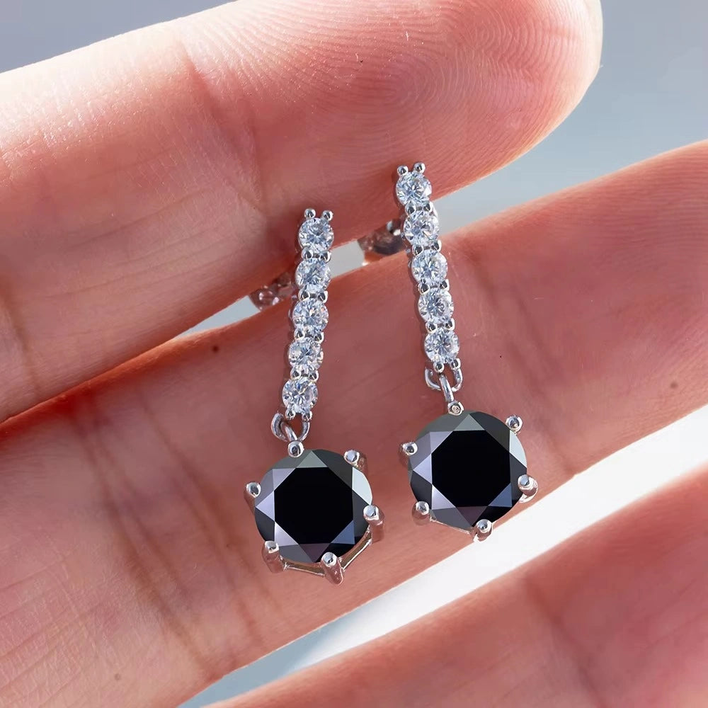 Hand holding a pair of black moissanite drop dangle earrings 2ct with clear cubic zirconia accent stones - Sensitive Stones