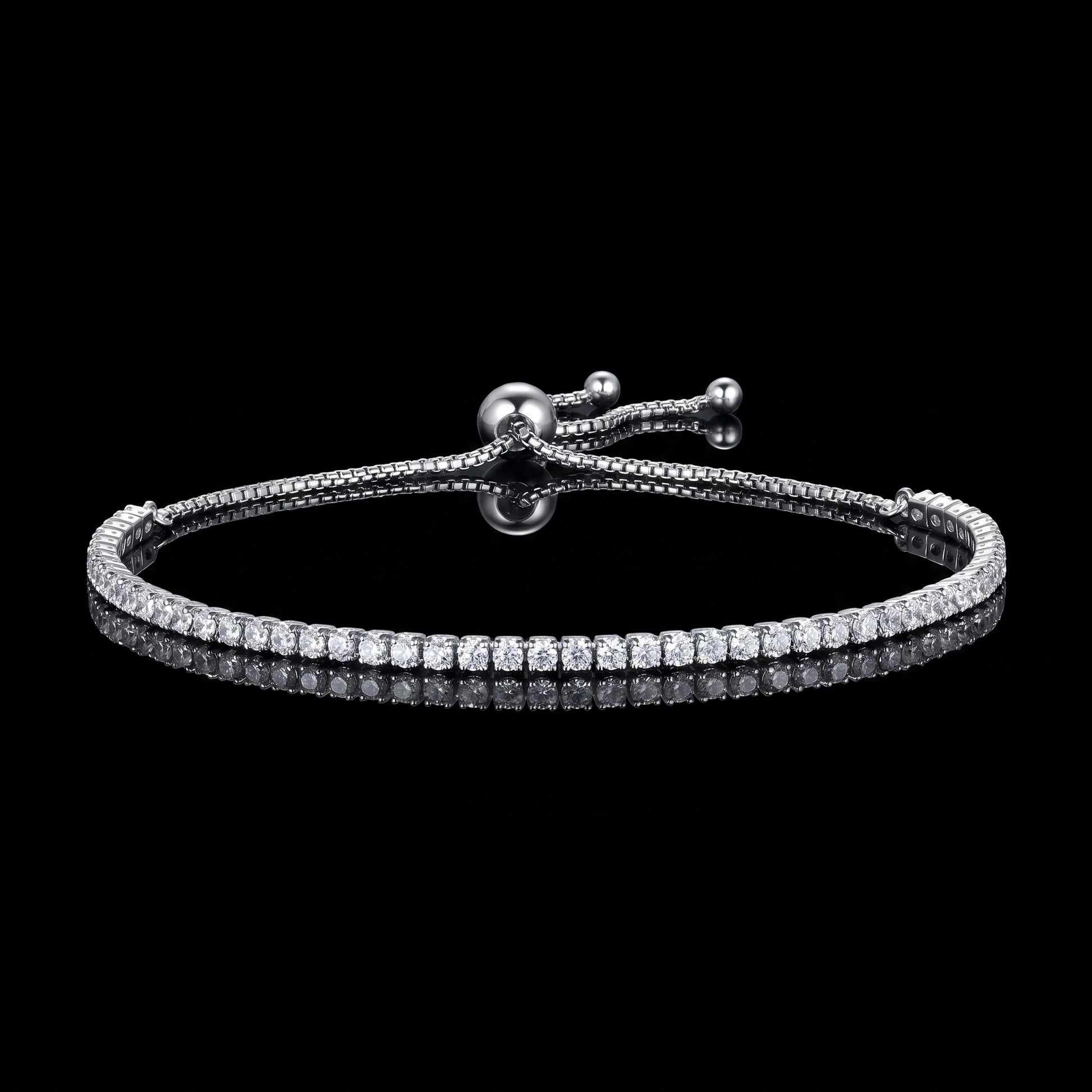 A 2mm moissanite bolo tennis bracelet with clear round-cut stones in 925 sterling silver with a white gold finish and sliding bolo closure, on a reflective black background - Sensitive Stones