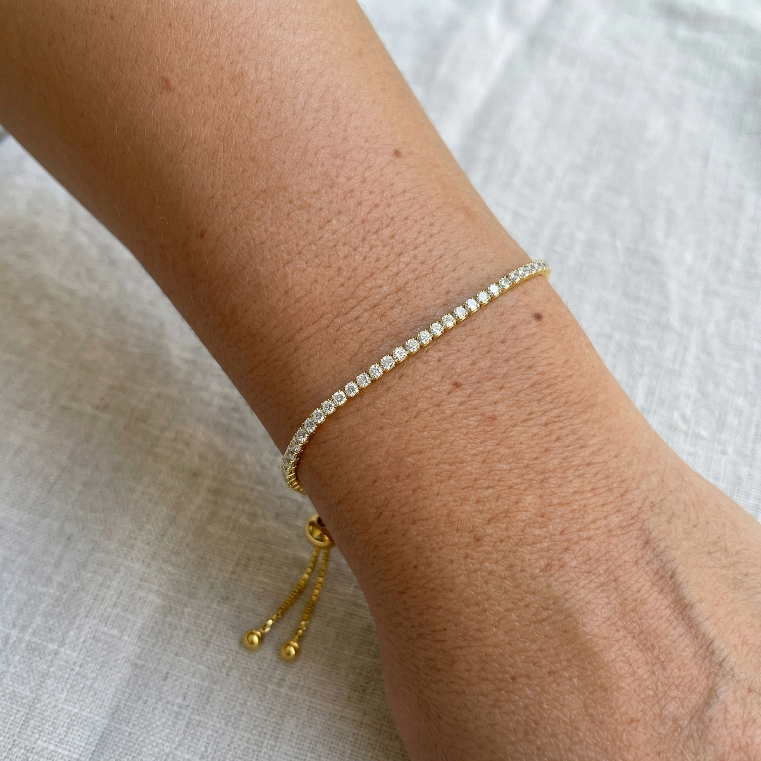 2mm 925 silver moissanite bolo tennis bracelet in 18k gold color on wrist showing edge-to-edge stone setting - Sensitive Stones