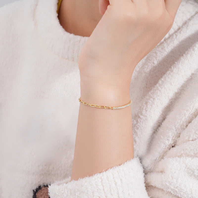 Dainty 2mm hybrid moissanite tennis bracelet with paperclip link in 18K yellow gold plating worn on hand, featuring adjustable chain and sparkling VVS1 stones.