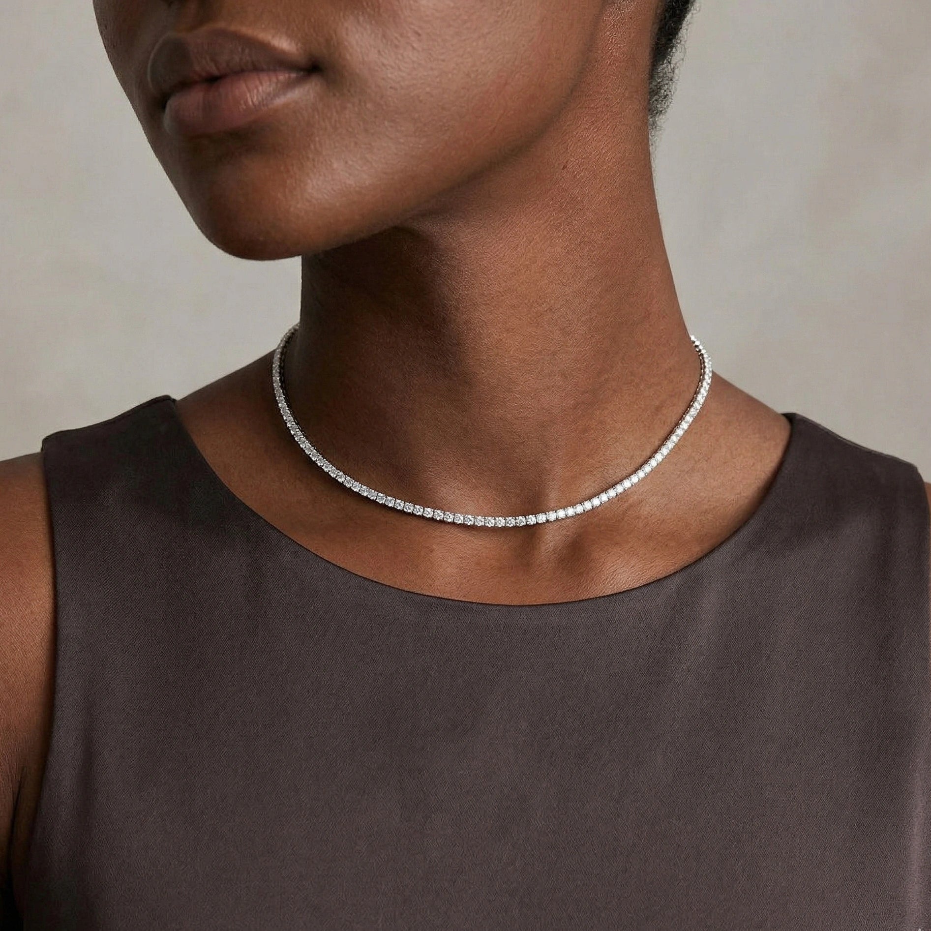 Woman wearing a 2mm moissanite tennis choker necklace in white gold, showing how the delicate, sparkly chain sits at the base of the neck with a sleeveless dress - Sensitive Stones