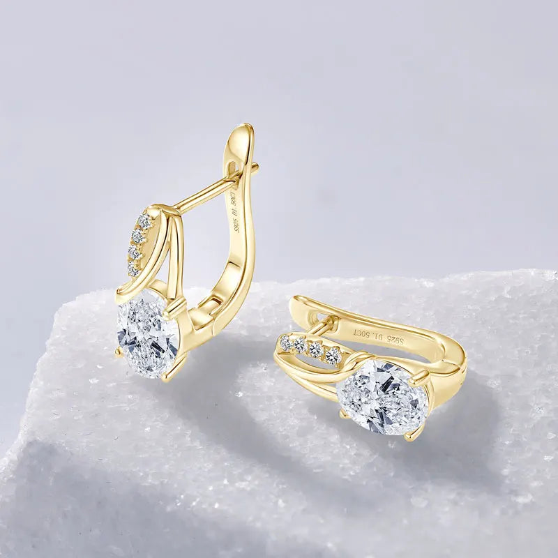 3CT oval Moissanite Huggie hoop earrings in 925 sterling silver and gold plating on a textured white surface - Sensitive Stones