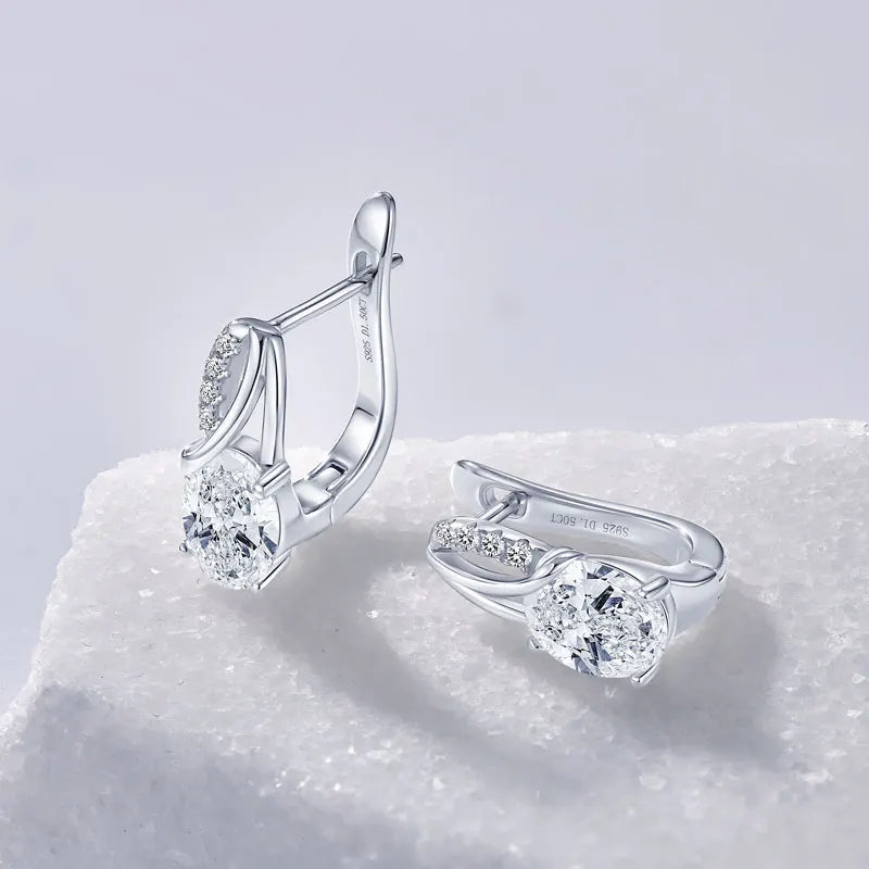 3CT oval Moissanite Huggie hoop earrings in 925 sterling silver on a textured white surface - Sensitive Stones
