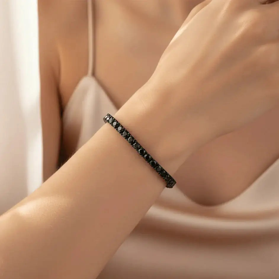 Woman wearing 3 mm black moissanite tennis bracelet in black gold plating, elegant wrist close-up with soft beige background – Sensitive Stones