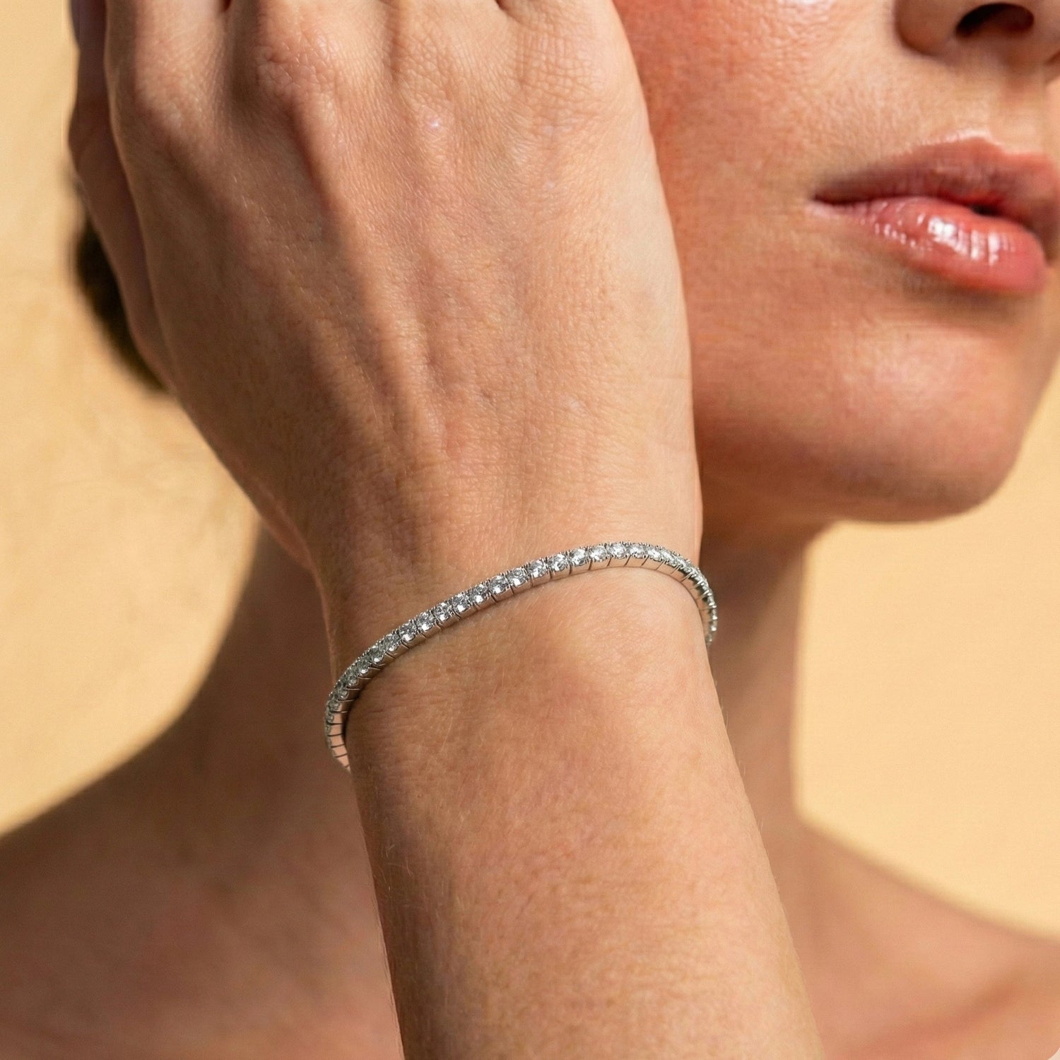 Close up of a woman styling a 3mm white gold elastic moissanite tennis bangle bracelet on wrist - Sensitive Stones