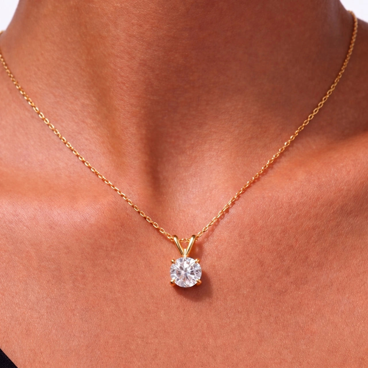 Woman wearing a 4-prong moissanite solitaire necklace in yellow gold - Sensitive Stones