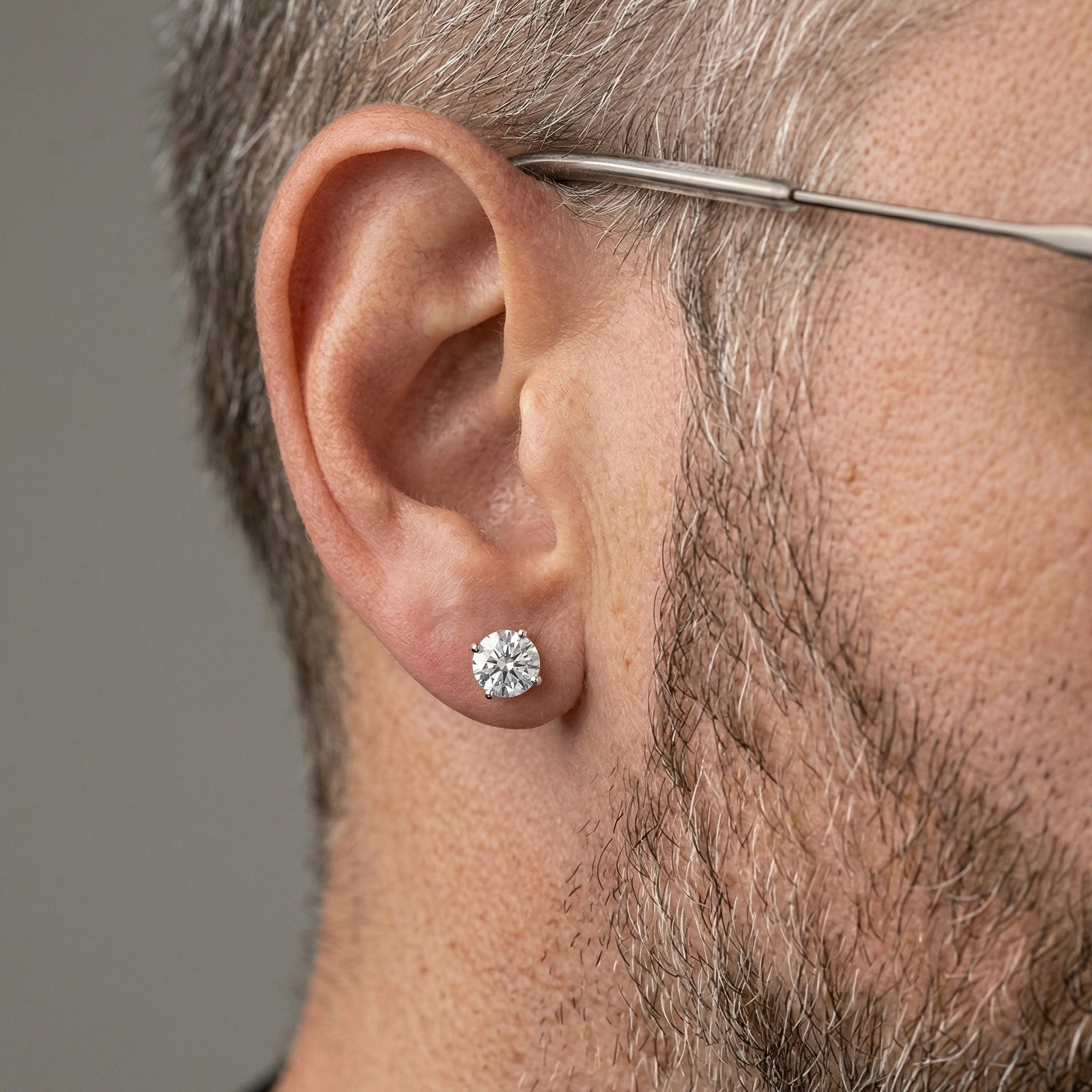  Man wearing 4-prong round cut moissanite solitaire stud earring 1ct 6.5mm unisex design – Sensitive Stones