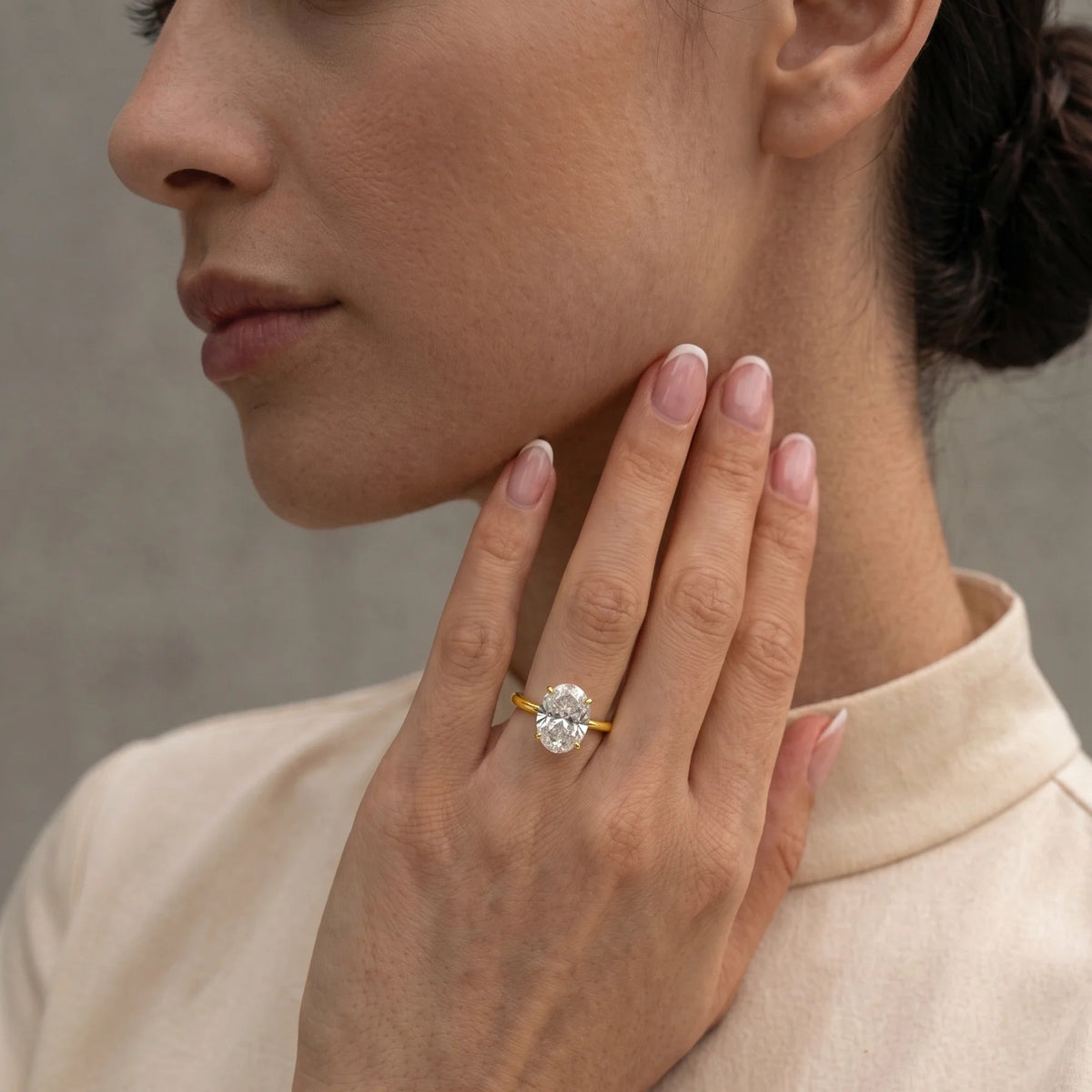 Woman wearing a 4-prong oval moissanite engagement ring in 14K gold filled on her ring finger