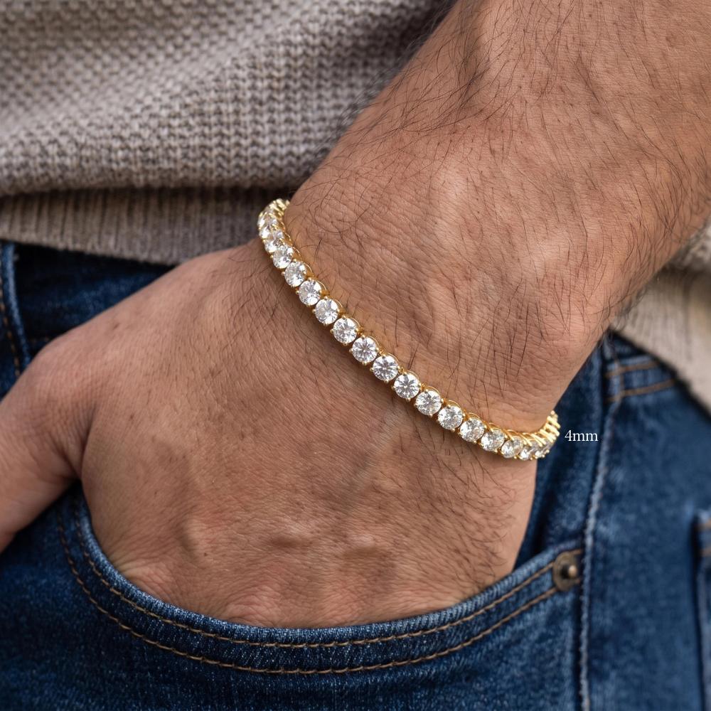 A 18k yellow gold plated 4mm moissanite tennis bracelet with clear stones worn on a man's wrist, with his hand in his blue jeans pocket - Sensitive Stones