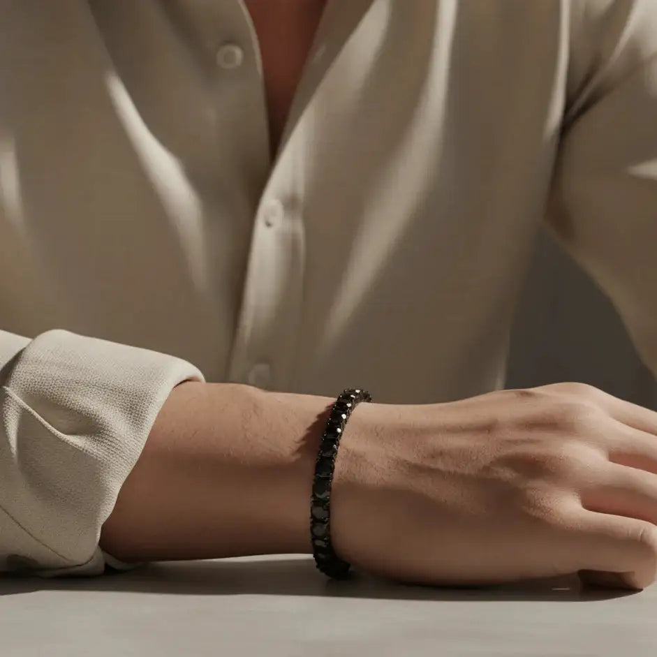 Man wearing 5mm black moissanite tennis bracelet in black gold plating, sand-beige shirt, minimalist lighting – Sensitive Stones