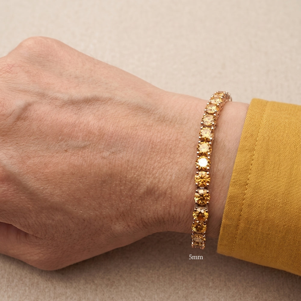 5mm golden yellow moissanite tennis bracelet in white gold plated sterling silver worn on a wrist with a mustard sleeve - Sensitive Stones