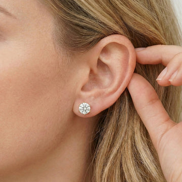 Close-up of a women wearing 6-prong moissanite solitaire stud earrings in 925 sterling silver and 18k gold plating showing sparkle and brilliance - Sensitive Stones