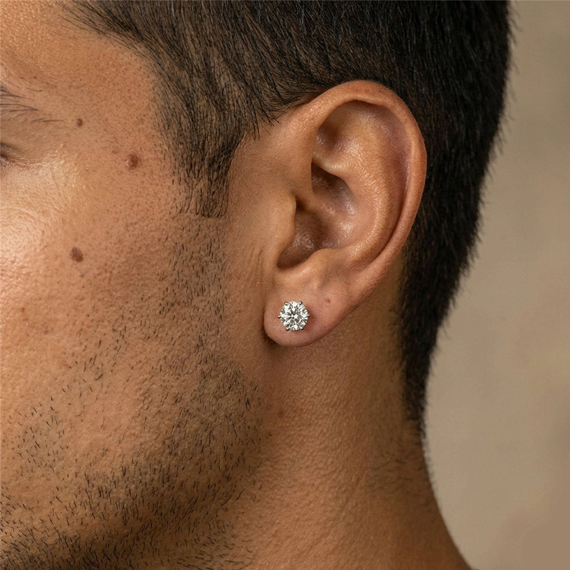 Close up of a man wearing 6-prong moissanite solitaire stud earrings in 925 sterling silver showing sparkle and brilliance - Sensitive Stones