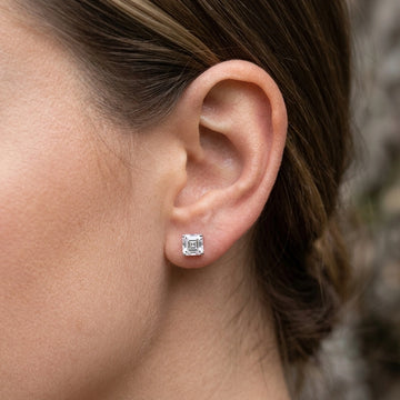 Woman wearing a 1ct asscher cut moissanite stud earring in white gold, close up on the earlobe - Sensitive Stones