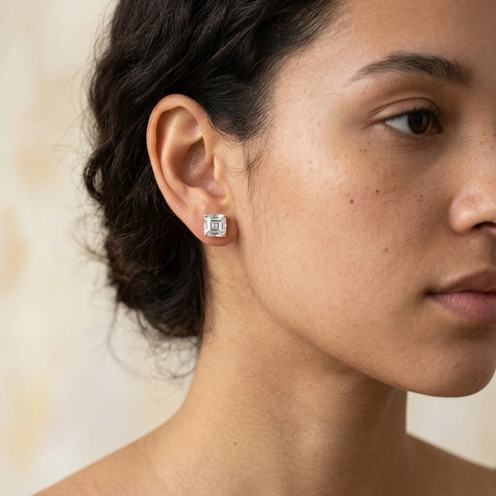 Woman wearing a 2ct asscher cut moissanite stud earring in yellow gold, close up on the earlobe - Sensitive Stones