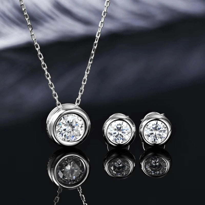 Bezel moissanite necklace and stud earrings set in 925 sterling silver styled on dark reflective surface - Sensitive Stones