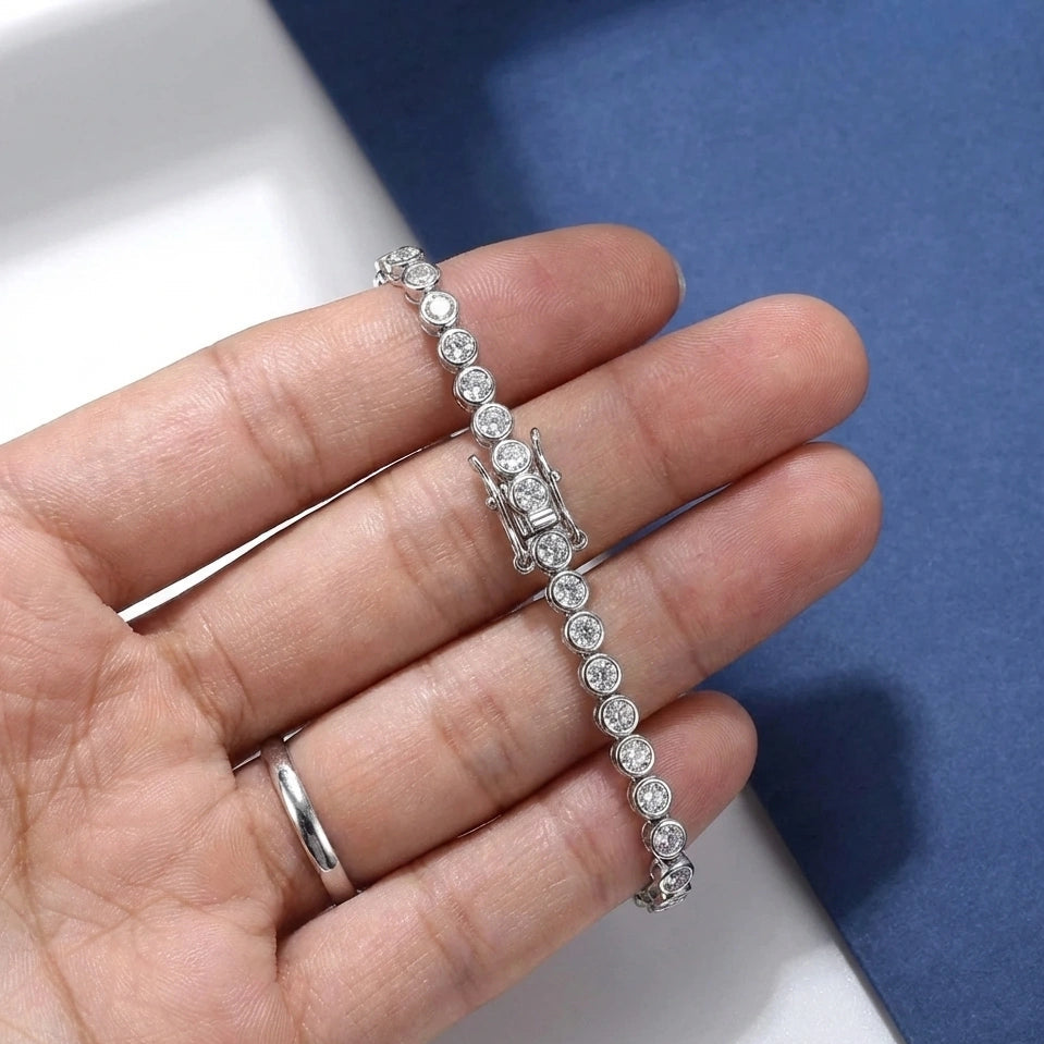 Hand holding a bezel moissanite tennis bracelet with 2mm D color VVS1 stones and secure double safety clasp in solid 925 sterling silver, 18K white gold plated - Sensitive Stones