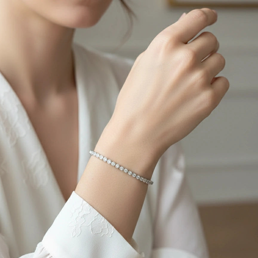 Woman wearing a dainty 2mm bezel moissanite tennis bracelet with D color VVS1 stones in 925 sterling silver, styled with a soft white blouse for an elegant bridal look - Sensitive Stones