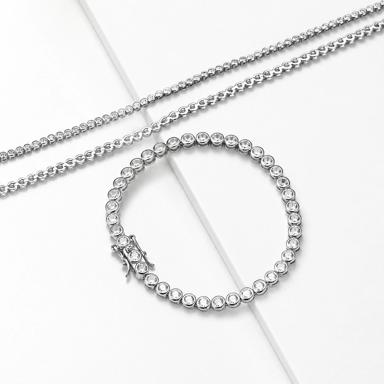 Bezel set moissanite tennis bracelet and matching chains in 925 sterling silver, D color VVS1 stones displayed on blue and white background - Sensitive Stones
