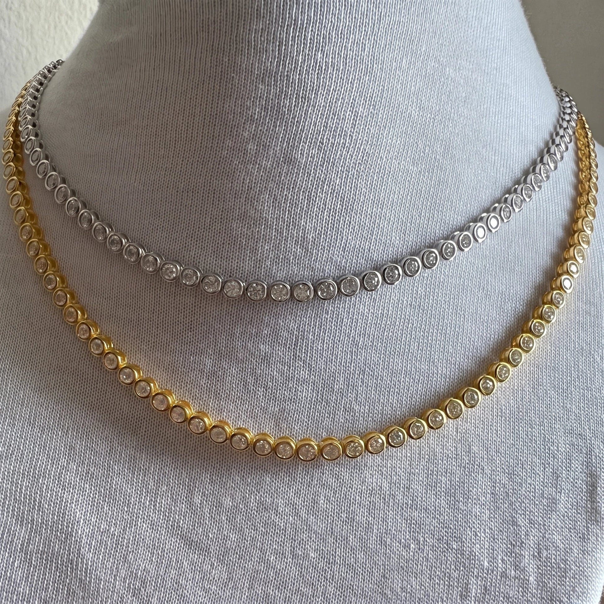 Bezel moissanite tennis necklaces in white gold and yellow gold layered on a display bust