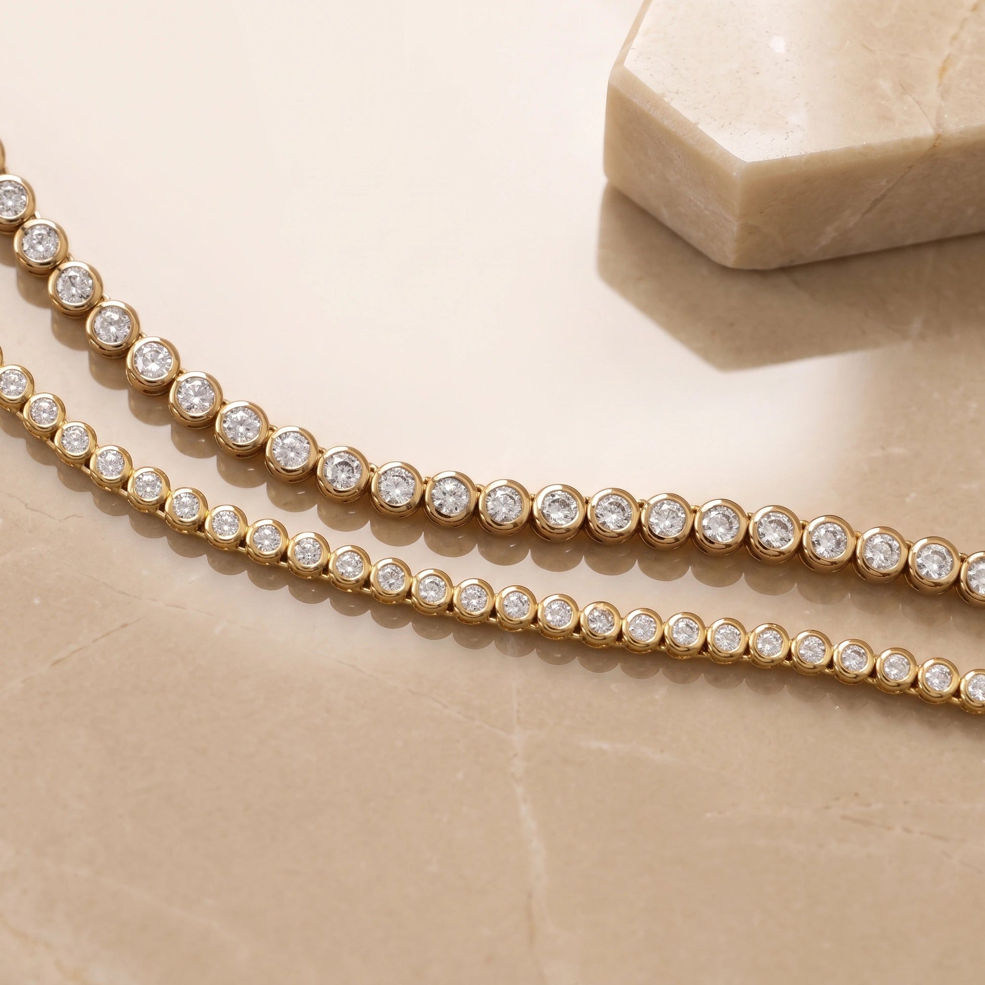 Bezel moissanite tennis necklace in 18K yellow gold showing the 2mm and 3mm stone sizes side by side