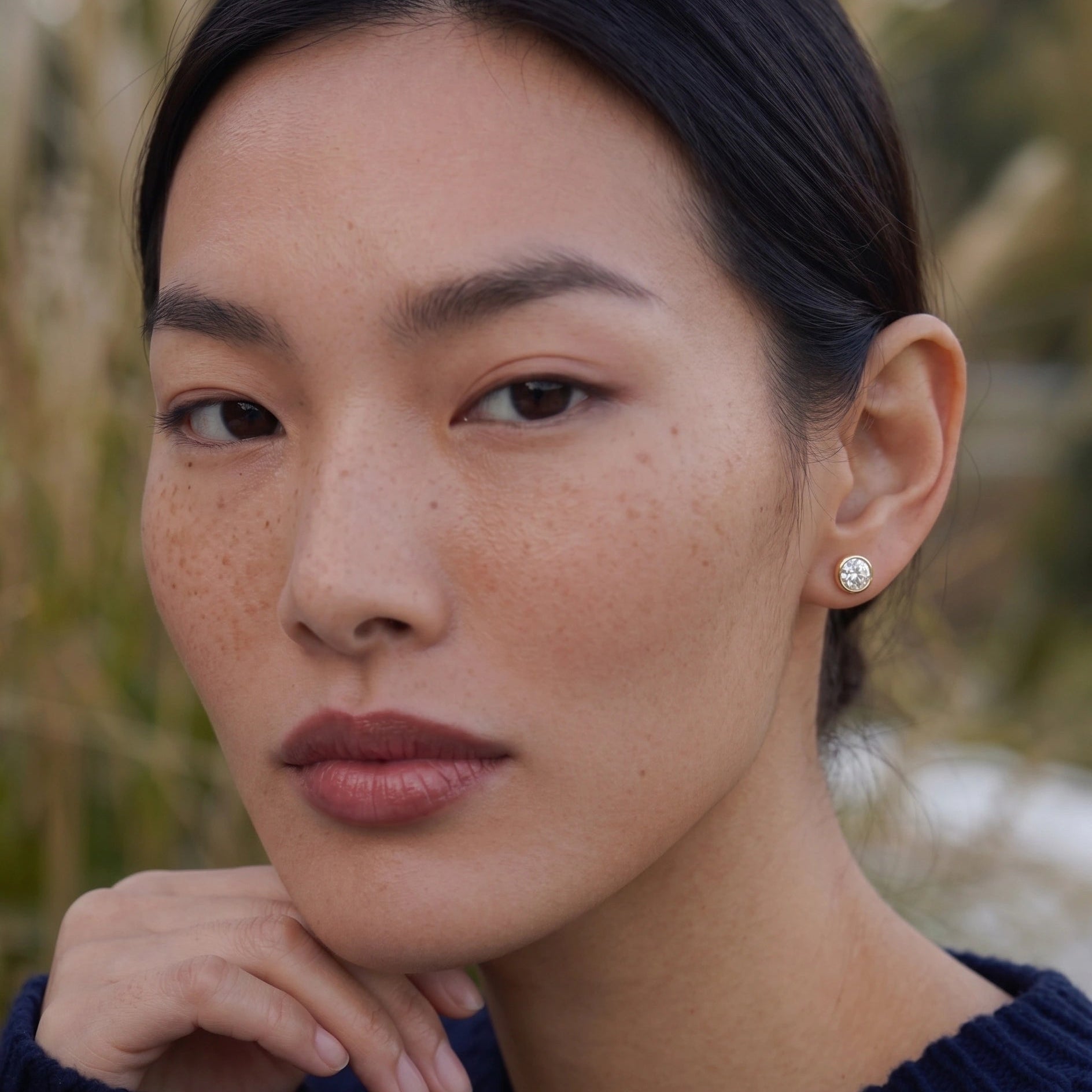 Bezel set moissanite stud on female model on one ear - Sensitive Stones