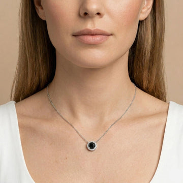 Black moissanite halo pendant necklace 1ct shown on woman’s neck, round black center stone with white halo on delicate sterling silver chain - Sensitive Stones