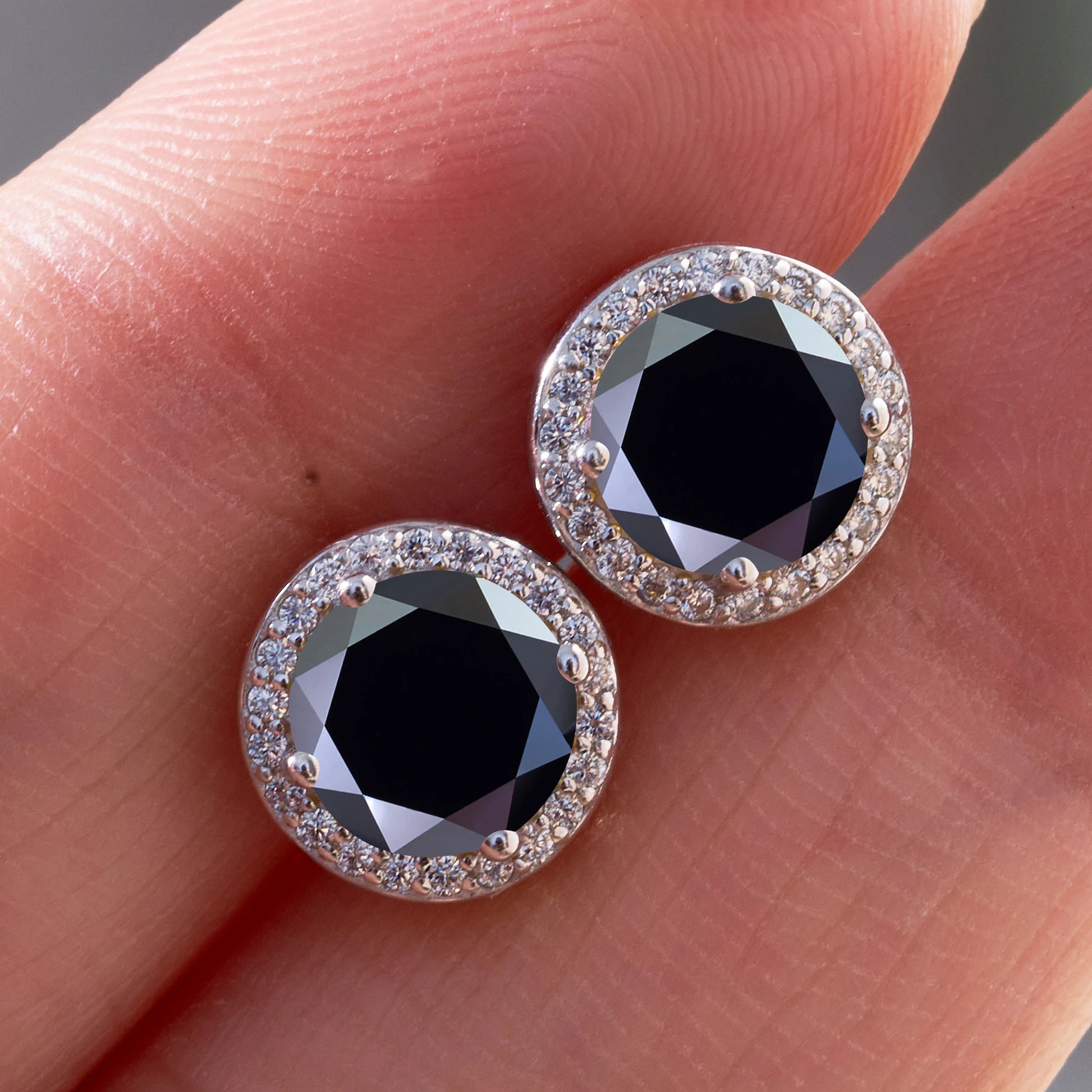 Black moissanite halo stud earrings in 925 sterling silver held on hand - Sensitive Stones