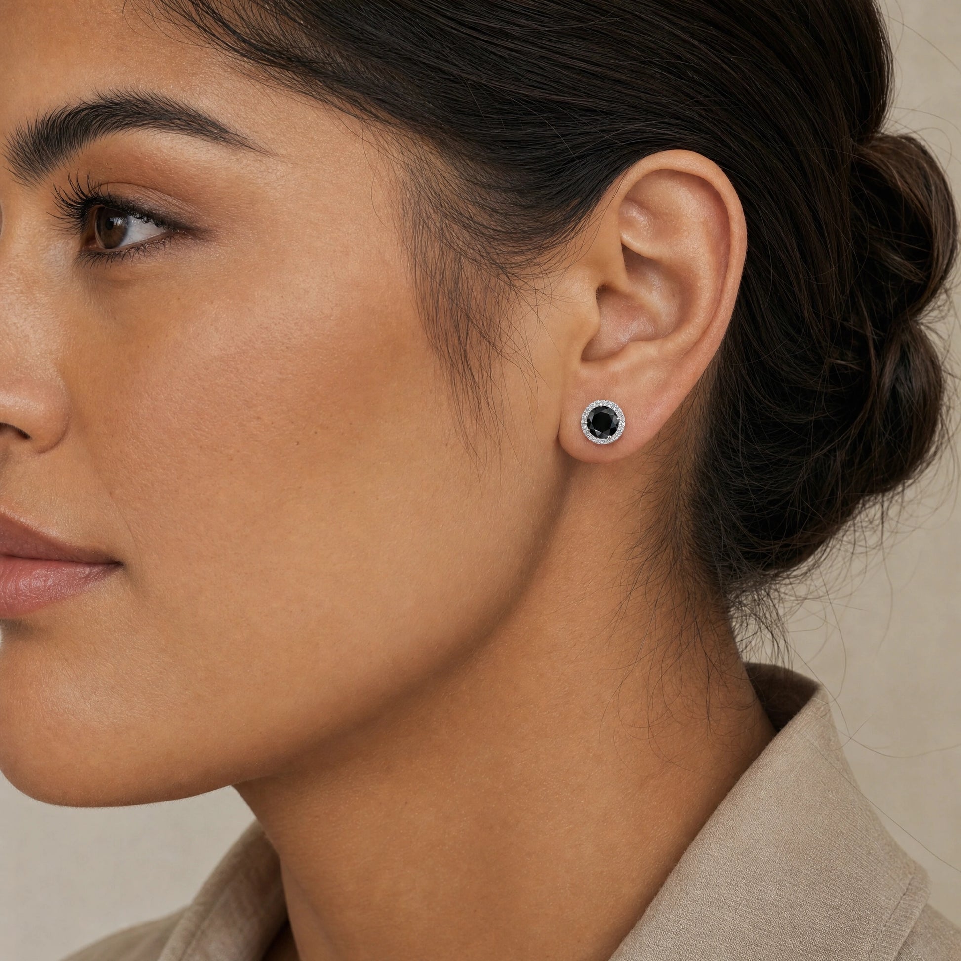 Woman wearing 1ct black moissanite halo stud earrings in 925 sterling silver showing natural size on ear - Sensitive Stones