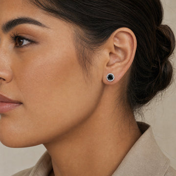 Woman wearing 1ct black moissanite halo stud earrings in 925 sterling silver showing natural size on ear - Sensitive Stones