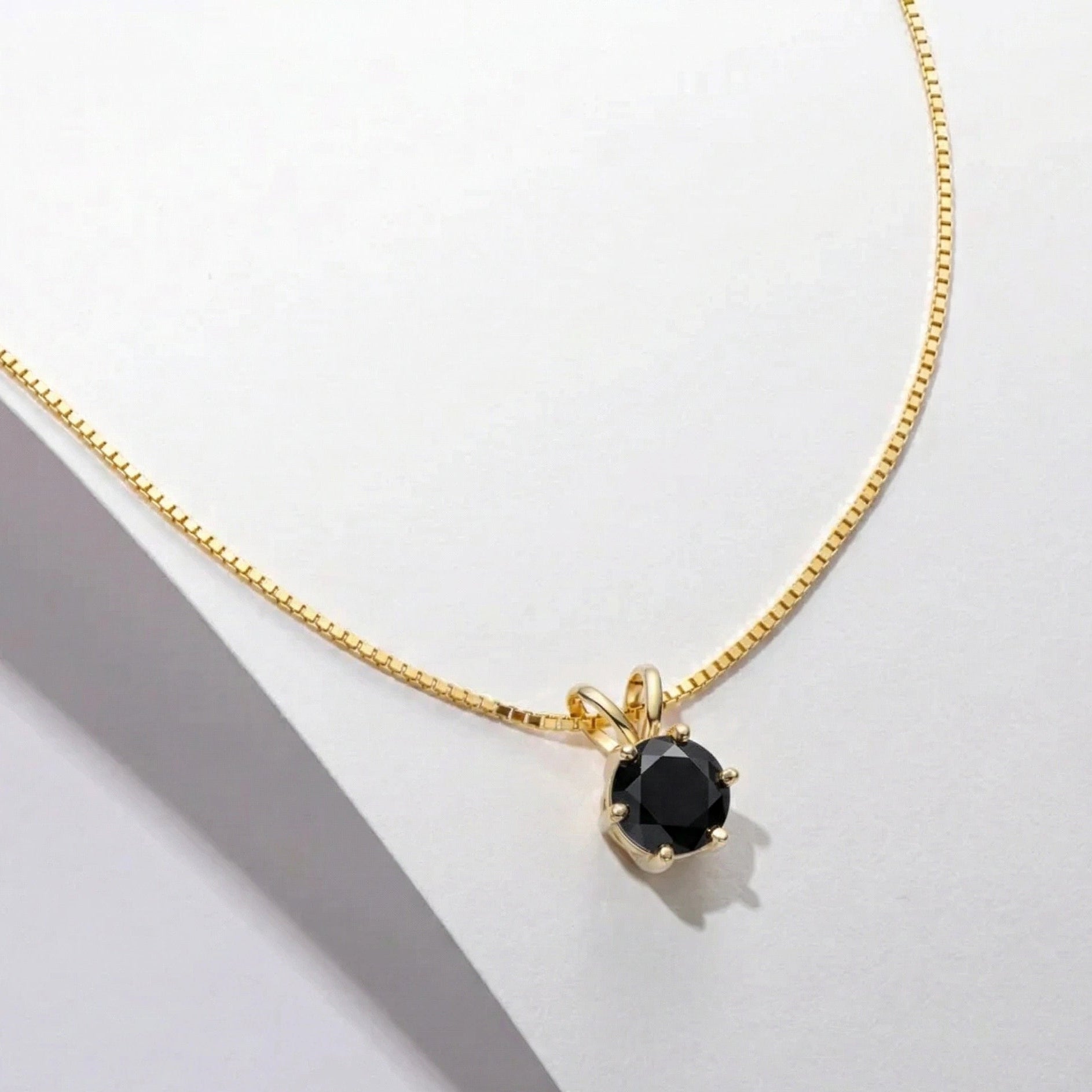 Black moissanite round solitaire pendant necklace with 18k gold plated box chain on white surface - Sensitive Stones