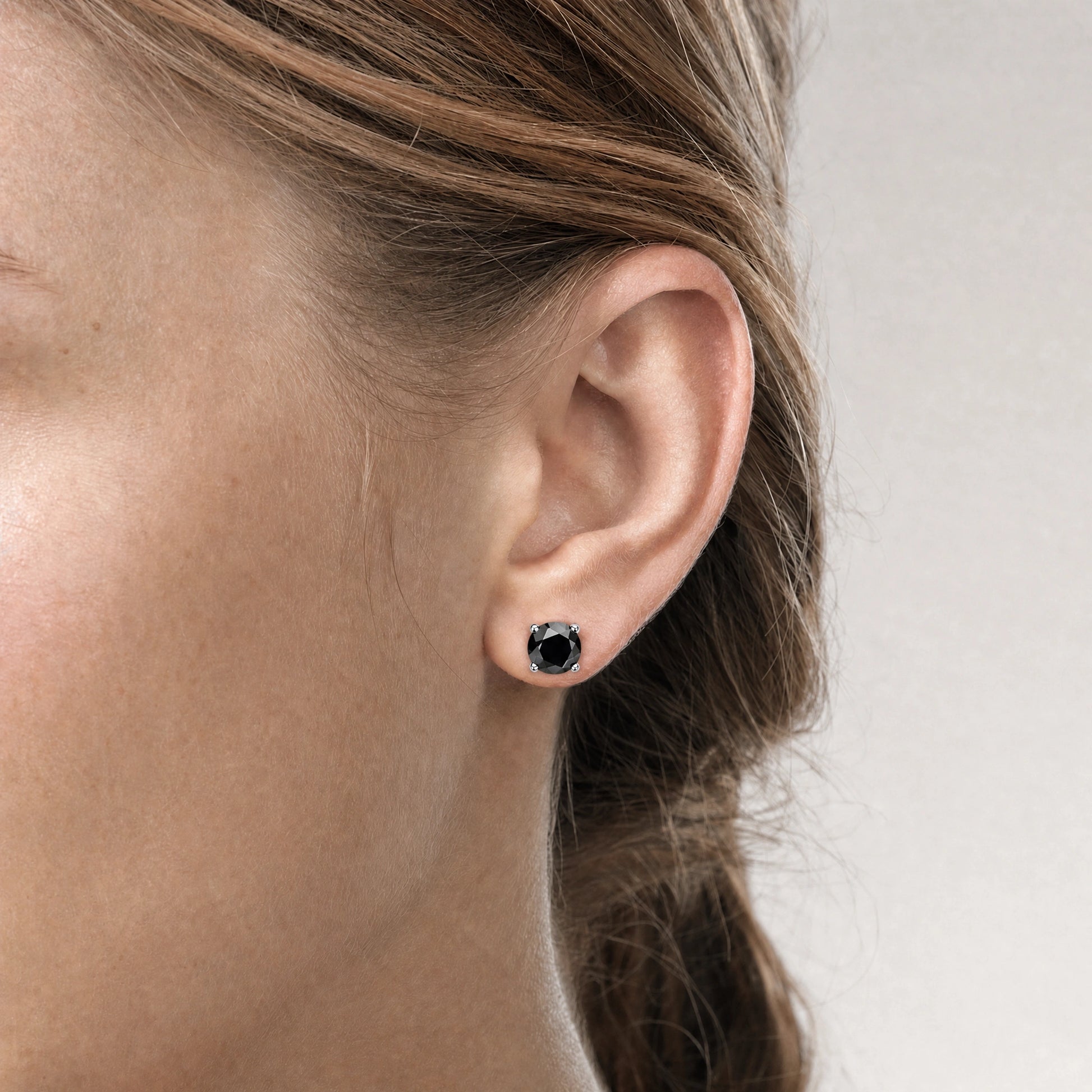 Woman wearing black moissanite stud earrings, round cut in a 4-prong silver setting - Sensitive Stones