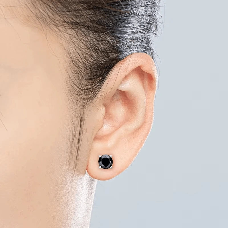 Close-up of an ear wearing a 4-prong black moissanite stud earring on a neutral background - Sensitive Stones