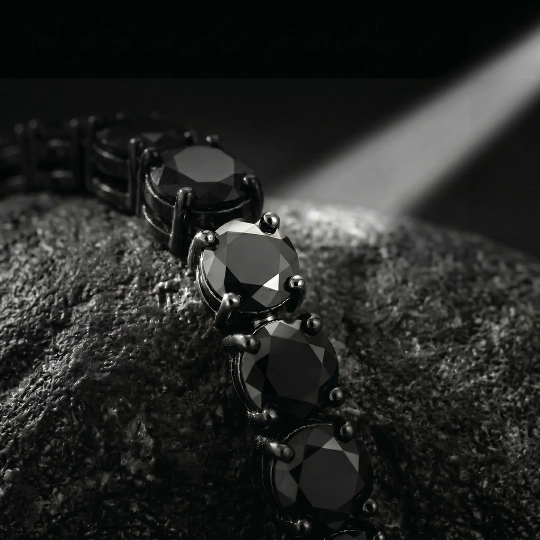 Macro close-up of black moissanite tennis bracelet showing faceted stones and 4-prong setting in dramatic dark lighting - Sensitive Stones