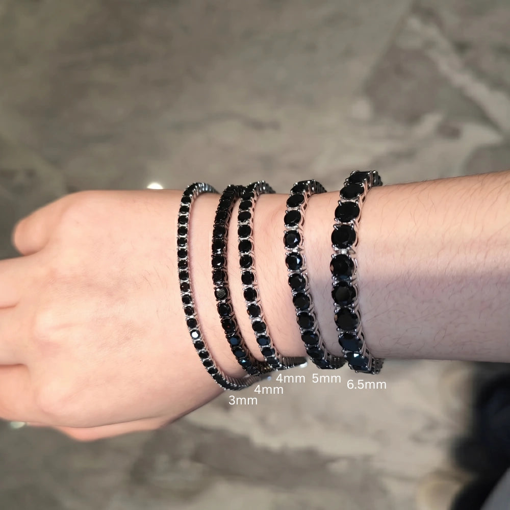Mens wrist wearing four black moissanite tennis bracelets showing 3mm 4mm 5mm and 6.5mm widths side by side for size comparison - Sensitive Stones