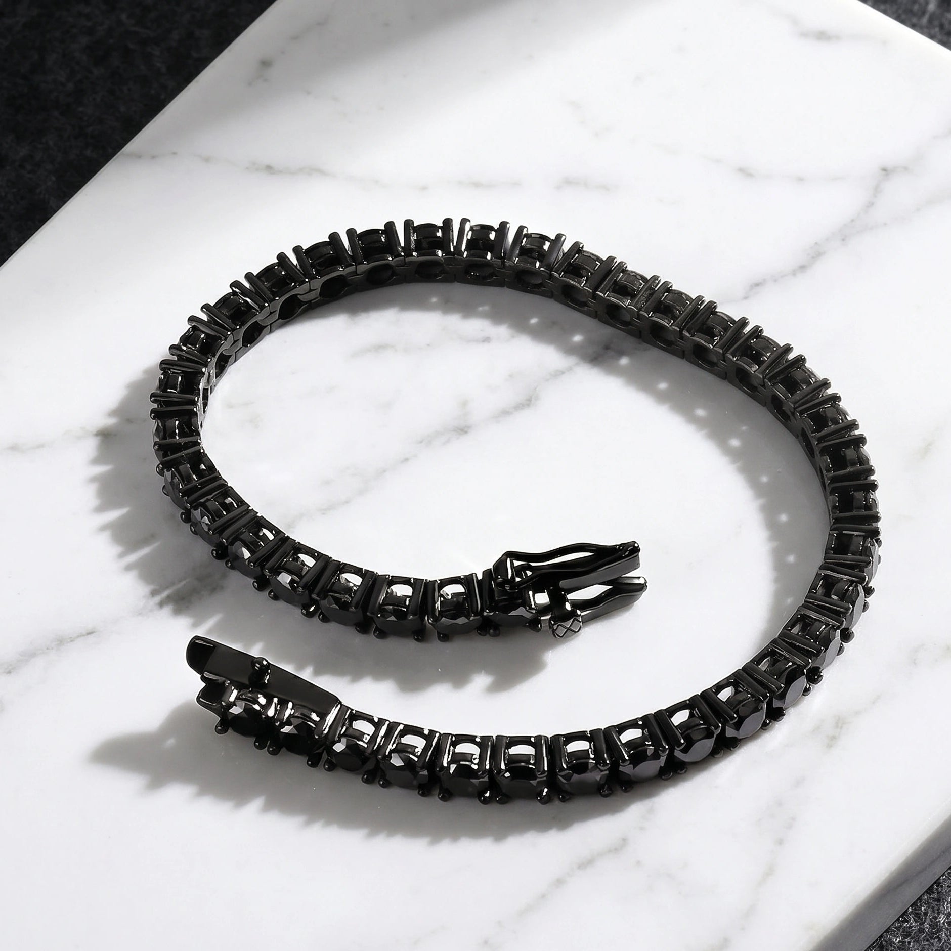 Black moissanite tennis bracelet with black gold plating on a marble surface - Sensitive Stones