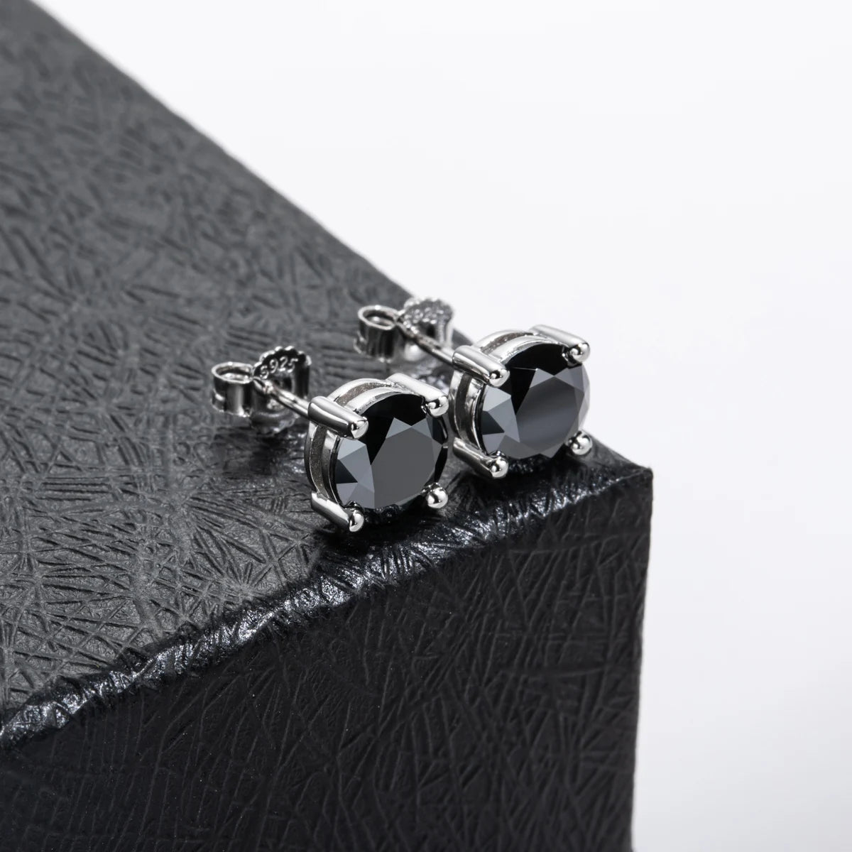 Black moissanite stud earrings, round cut, set in 925 sterling silver with 18K gold plating set on a textured surface | Sensitive Stones